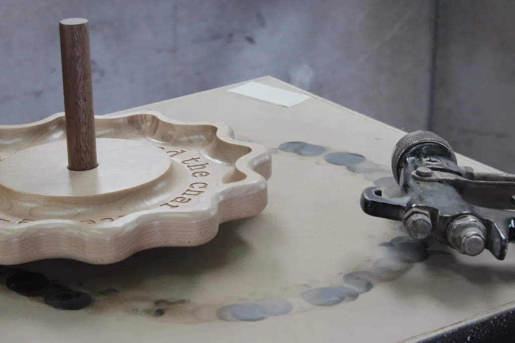 charcuterie tray sitting in wood finishing booth next to spray gun