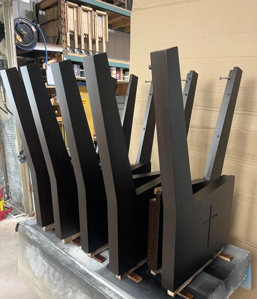 A row of finished oak pew ends lined up in the shop to cure after receiving stain and lacquer coats.